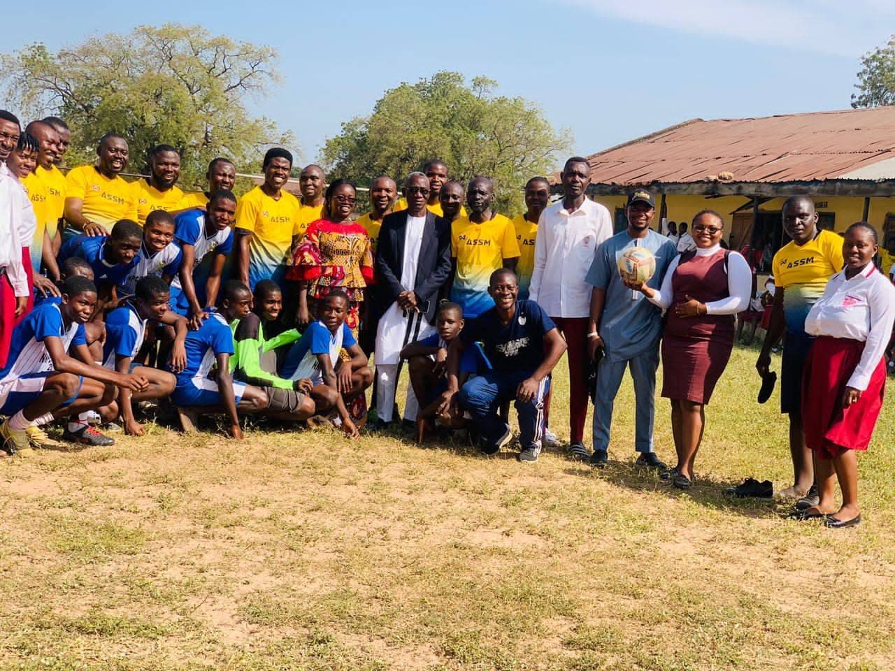 A large sports-day group on the school field, many in yellow jerseys
